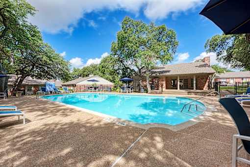 A pool surrounded by trees and a house.