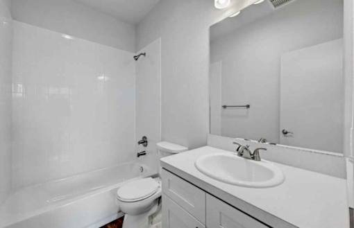 A white bathroom with a toilet, sink, and bathtub.