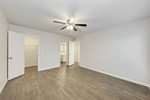 A room with a ceiling fan and wooden flooring.