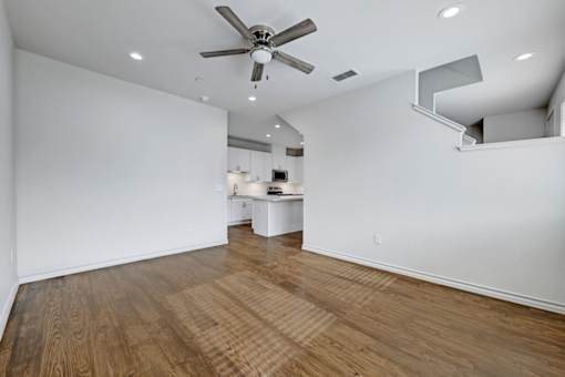 A room with a ceiling fan and wooden flooring.