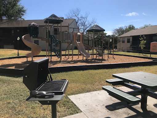 A playground with a slide, swings, and picnic tables.