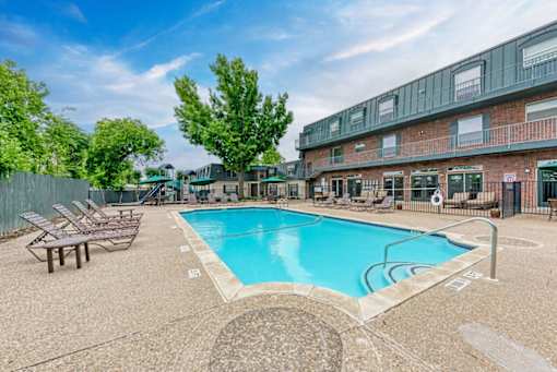 A small pool with a bench and a fence in front of a building.