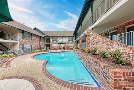 A swimming pool surrounded by a brick wall and a stone patio.