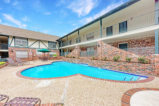 A swimming pool in a courtyard surrounded by a brick wall.
