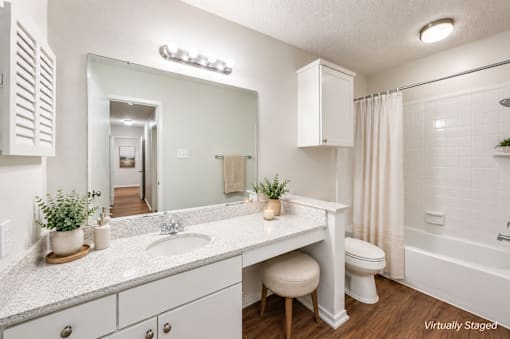 A white bathroom with a vanity, toilet, and shower.