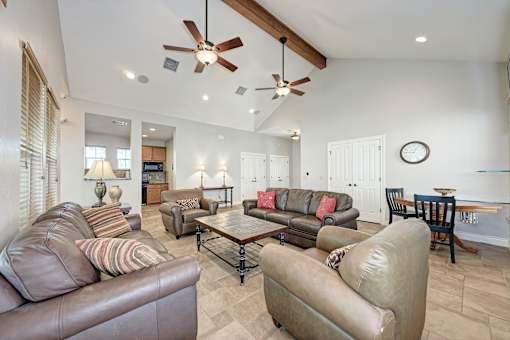 A living room with brown leather couches and a ceiling fan.