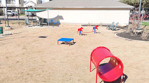 A red chair is in the foreground of a playground.