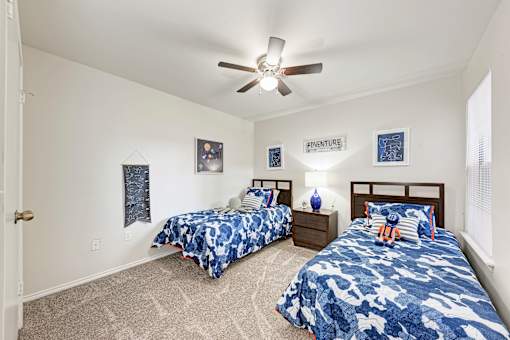 A bedroom with two beds and a ceiling fan.