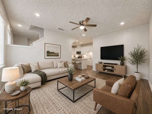A living room with a white couch, a coffee table, and a television.