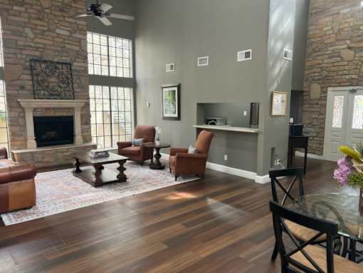 A living room with a stone fireplace and wooden floors.