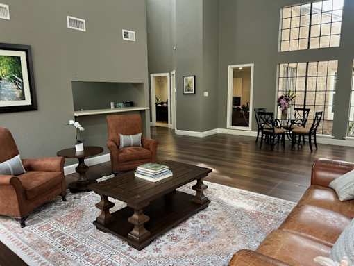 A living room with brown leather furniture and a rug.