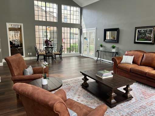 A living room with brown leather furniture and a large window.