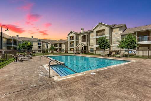A large swimming pool in front of apartment buildings.