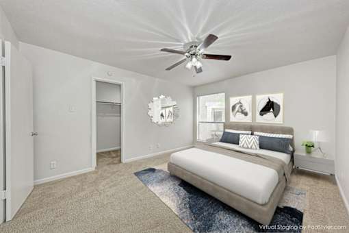 A bedroom with a bed, a ceiling fan, and pictures on the wall.