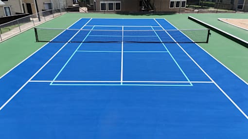 A blue tennis court with white lines and a net.