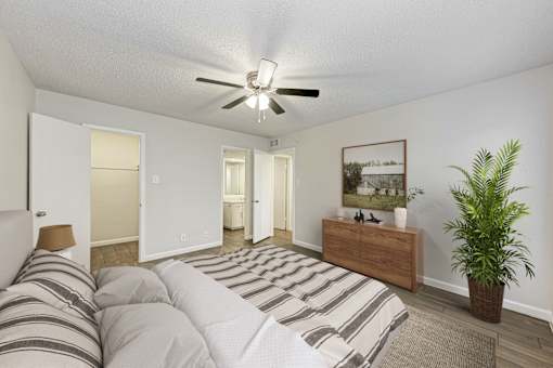 A bedroom with a bed, dresser, and ceiling fan.