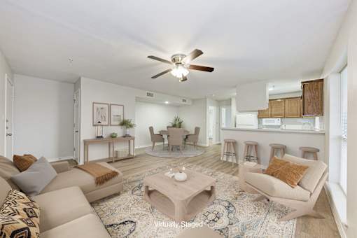 A living room with a beige couch, a coffee table, and a ceiling fan.