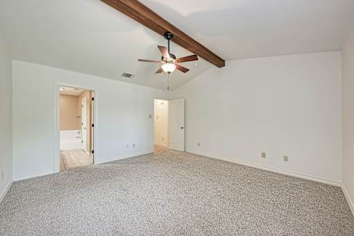 A spacious room with a ceiling fan and carpeted floor.