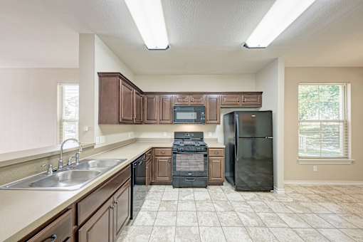 A kitchen with brown cabinets and a black refrigerator.