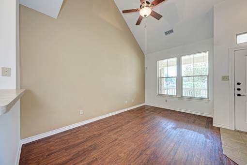 A room with a ceiling fan and wooden flooring.