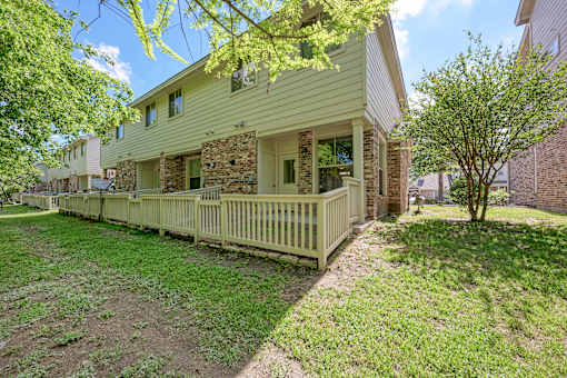 A house with a green lawn and a tree in front.