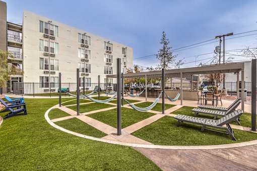 A playground with a slide, swings, and a seesaw in front of a building.