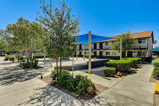 A building with a blue awning is surrounded by trees and bushes.