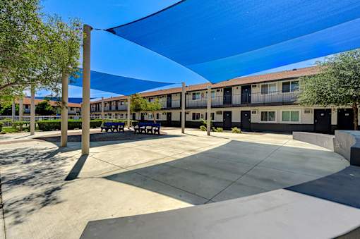 A sunny day at the courtyard of a building with benches and trees.