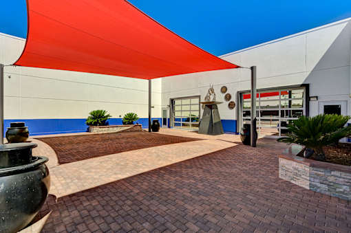 A red shade structure is over a brick walkway.