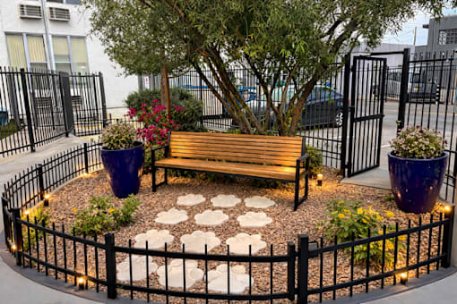A small park with a bench, a tree, and flower pots.