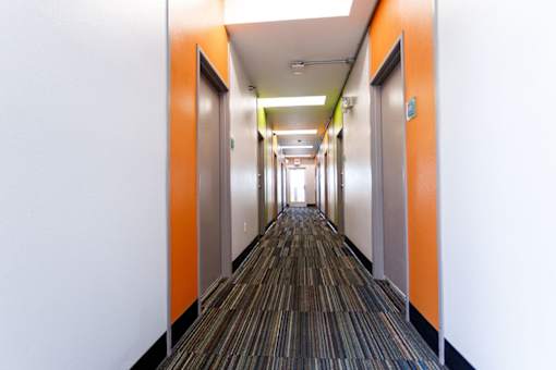A long hallway with orange doors and striped carpeting.