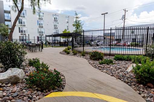 A walkway with a yellow line in the middle leads to a black fence and a pool.