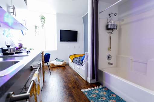 A modern kitchen with a blue chair and a white bathtub.