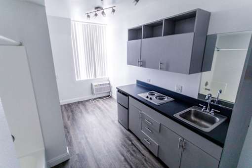 A kitchen with a sink, stove, and cabinets.