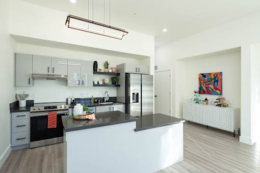 A modern kitchen with a black countertop and stainless steel appliances.