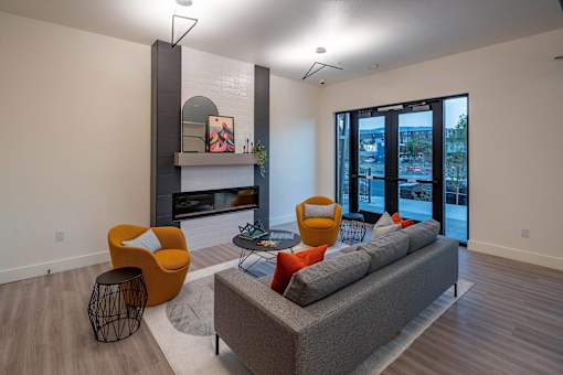 A living room with a grey couch, orange chairs, and a fireplace.