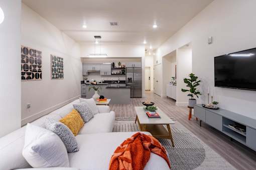 A modern living room with a white sofa and a television on the wall.