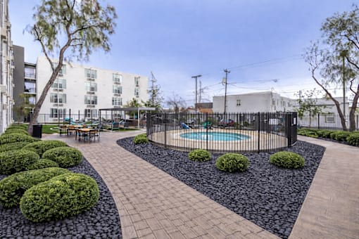 A black and white garden with a pool and a building in the background.