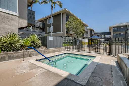 A pool in a backyard with a slide and a fence.