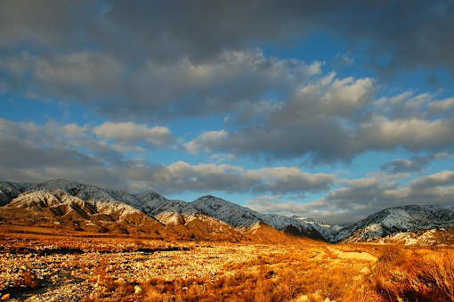 A mountain range with snow on the peaks and a cloudy sky.