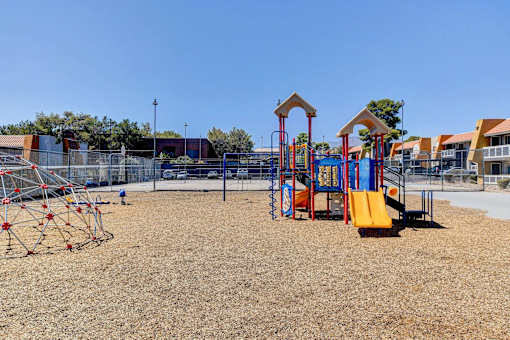 A playground with a yellow slide and red and blue play structures.