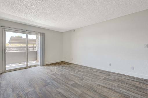 A room with a sliding glass door and wood flooring.