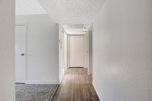 A long hallway with white walls and wood flooring.