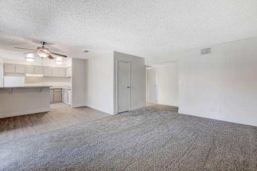 A room with a carpeted floor and a ceiling fan.