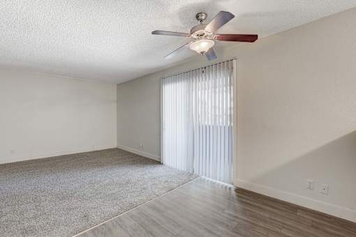 A room with a ceiling fan and a window with blinds.