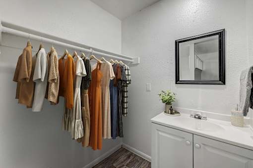 A row of clothes hanging on a rail in a white room.