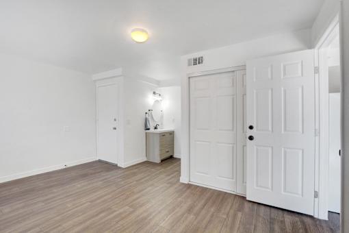 A room with white doors and a cabinet with a lamp on it.