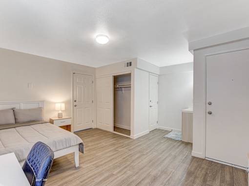 A bedroom with a bed, chair, and wardrobe.