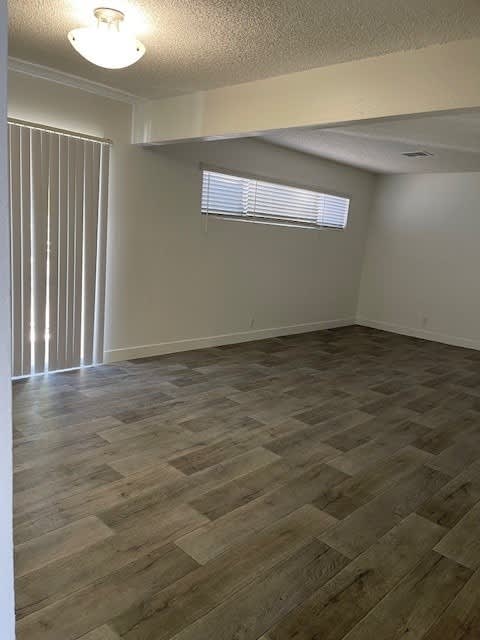 A room with wooden flooring and a window with blinds.