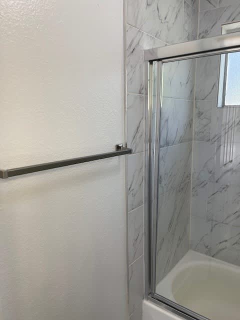 A white bathtub sits next to a glass shower door.